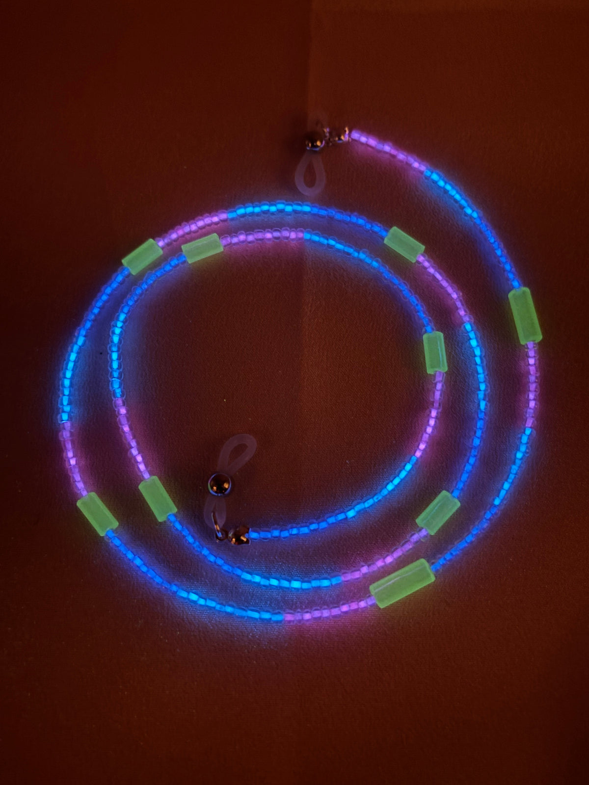 Luminous glow in the dark multicolored beaded lanyard coiled in the dark.