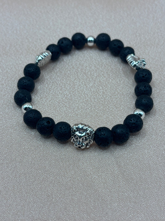 Lionheart handcrafted stretch bracelet featuring textured black lava stone beads, polished metallic accents, and a detailed silver lion charm centerpiece by Beadiful Adornments.