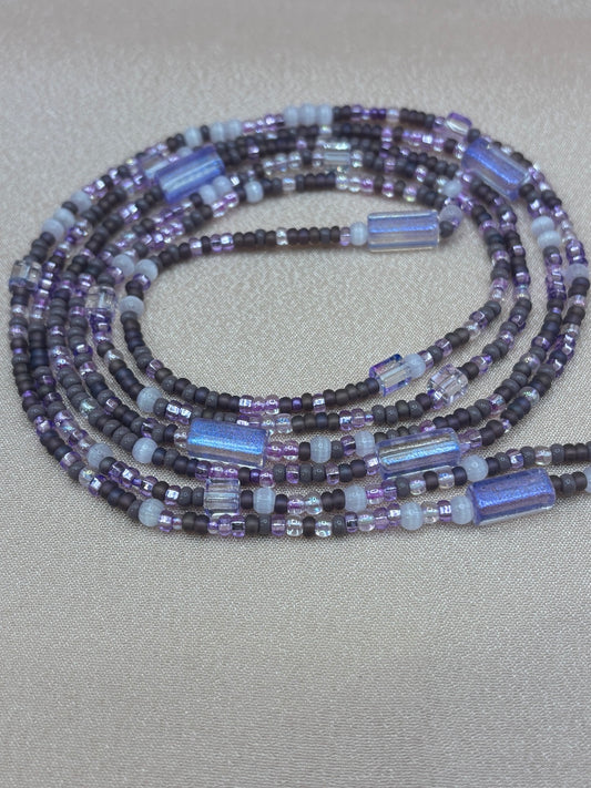 Handmade beaded waist beads in layers of matte dark purple, lilac, iridescent blue-purple tubes, and translucent seed beads