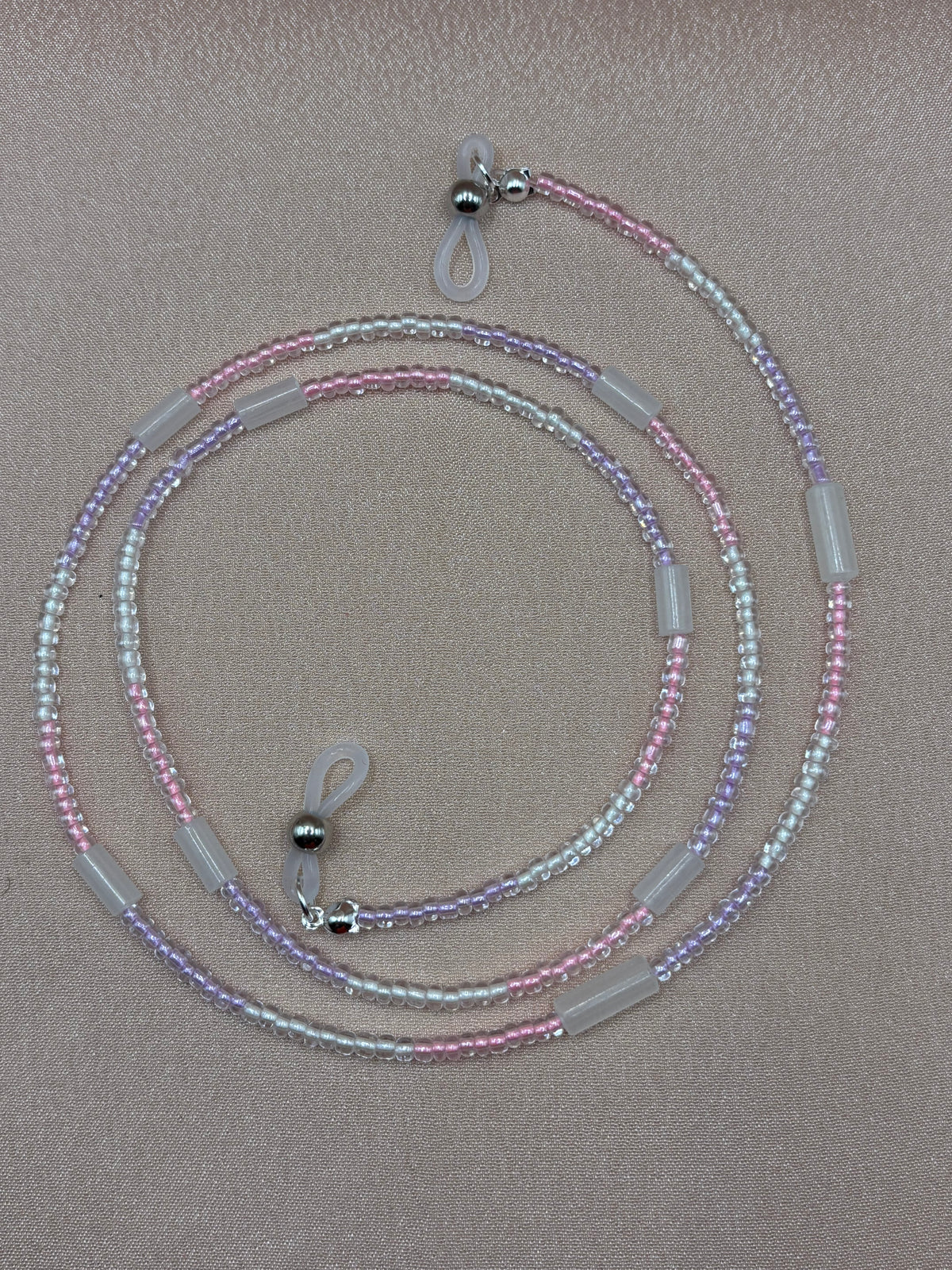 Clear glow in the dark beaded glasses strap coiled on a gray background.