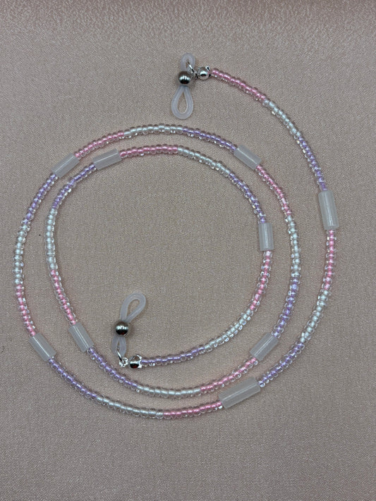 Clear glow in the dark beaded glasses strap coiled on a gray background.