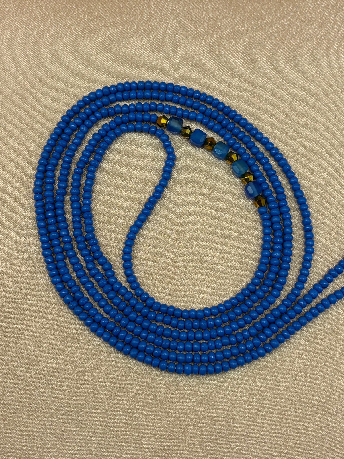 Royal Opulence blue beaded eyeglass chain with natural blue agate crystals coiled on a plain background.
