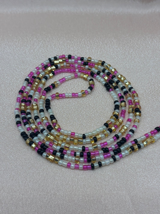 Sassy handcrafted waist beads featuring a vibrant pattern of pink, black, white, and metallic gold glass seed beads by Beadiful Adornments.